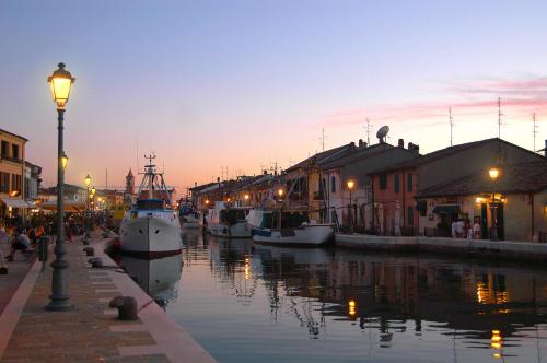 a group of boats docked in a canal at sunset at Piccolo Hotel in Cesenatico