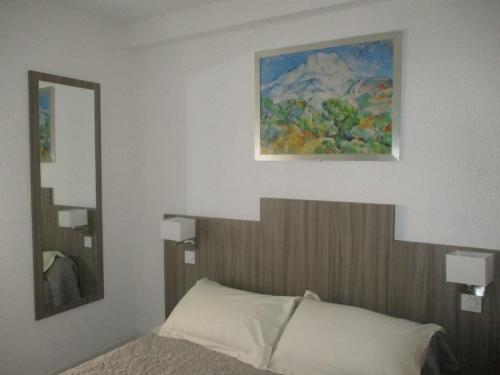 a bedroom with a bed and a painting on the wall at Hotel Du Commerce in Pont-Saint-Esprit