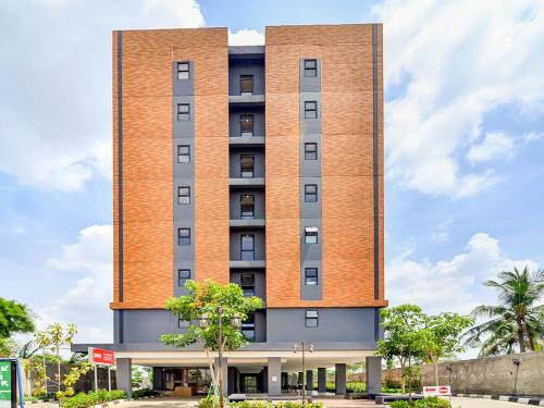 ein hohes rotes Backsteingebäude mit Bäumen davor in der Unterkunft Collection O 92440 Urban Town Apartment Karawang in Telukjambe