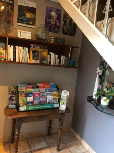 une pile de livres assis sur une table sous un escalier dans l'établissement Hotel Du Commerce, à Pont-Saint-Esprit