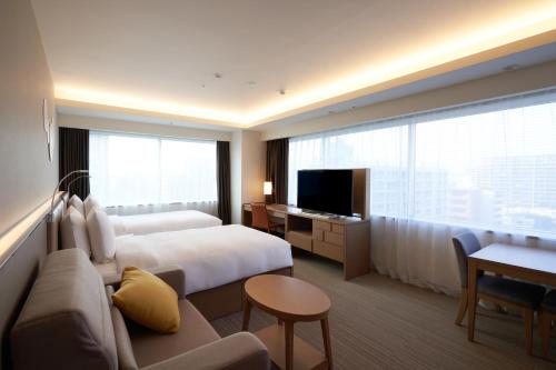 a hotel room with a bed and a couch and a tv at Holiday Inn & Suites Shin Osaka, an IHG Hotel in Osaka
