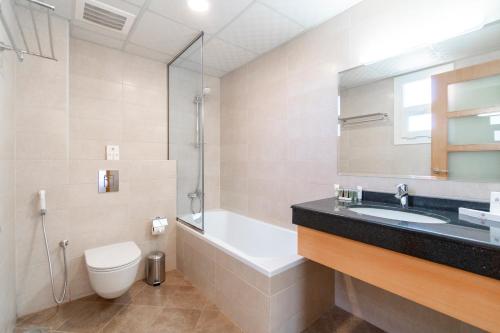 a bathroom with a sink and a tub and a toilet at Sama Muscat Hotel in Al Khawḑ