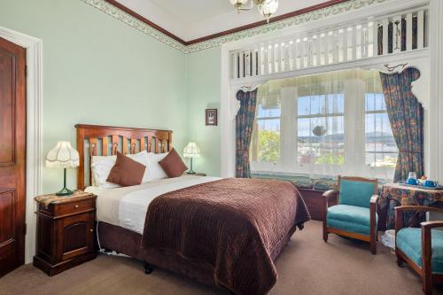 a bedroom with a bed and a chair and a window at Orana House in Hobart