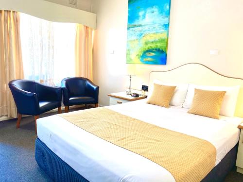 a hotel room with a bed, chair, desk and television at Golfview Motor Inn in Wagga Wagga