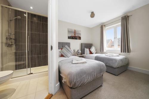 a bedroom with two beds and a shower and a bathroom at London Heathrow Living Holywell Serviced Houses - 3 and 4 bedrooms By Ferndale in Stanwell