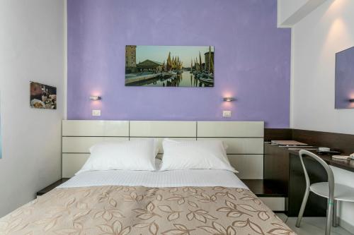 ein Schlafzimmer mit einem Bett und einer lila Wand in der Unterkunft Hotel Baya - in centro, sul mare in Milano Marittima