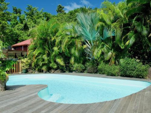 a swimming pool in front of a house with palm trees at Le Domaine du Rocher Noir in Pointe-Noire