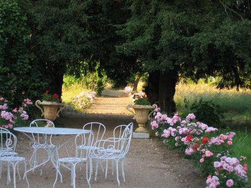 une table et des chaises dans un jardin fleuri dans l'établissement Chateau de la Rue, à Cour-sur-Loire