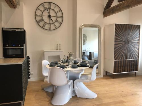 a dining room with a table and chairs and a clock at My Pad Provence 3 in Avignon