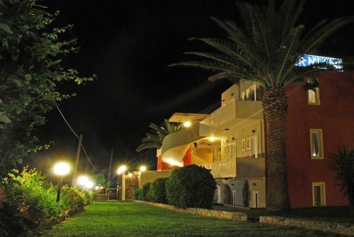 a building at night with a palm tree next to it at Ermioni Hotel in Georgioupolis