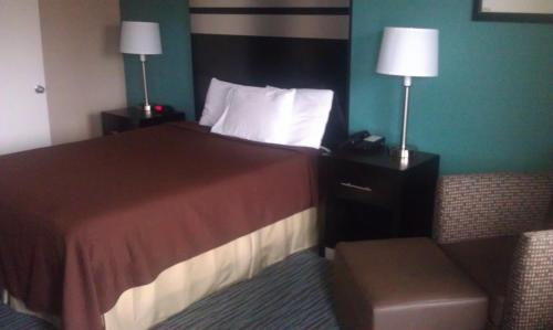 a hotel room with a bed and a chair and lamps at GuestHouse Inn Dothan in Dothan
