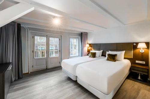 a hotel room with two beds and a window at NH Collection Barbizon Palace Apartments in Amsterdam