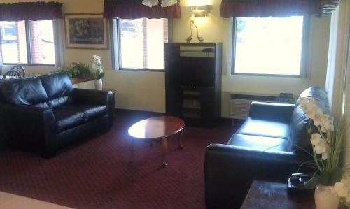 a living room with couches and a table and windows at GuestHouse Inn Dothan in Dothan