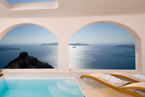 a room with a swimming pool with a view of the ocean at Gold Suites - Small Luxury Hotels of the World in Imerovigli