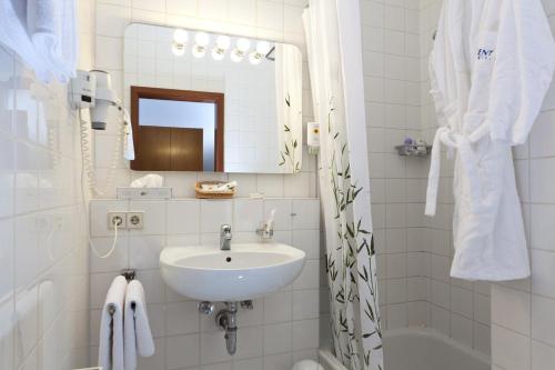 a white bathroom with a sink and a mirror at Business apartment in 3 star hotel Daimler Nah in Sindelfingen