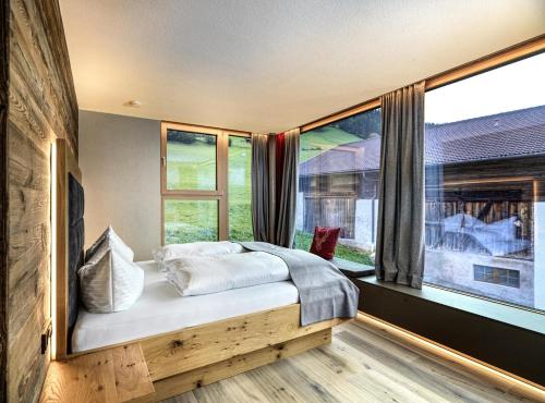 a bedroom with a bed and a large window at Sporerhof Dolomitenlogen in Obergaimberg