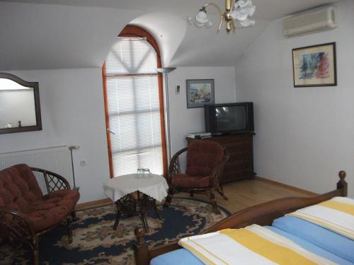a bedroom with a bed and a tv and a window at Ria Panzio in Esztergom