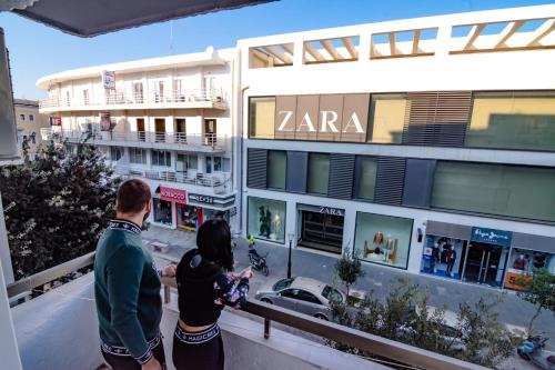 a man and woman standing on a balcony looking at a street at N E P center Hotel Rodos in Rhodes Town