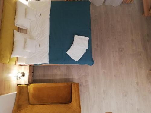 Cette chambre comprend un lit avec des oreillers blancs et une chaise. dans l'établissement U ŹRÓDEŁ, à Wisła