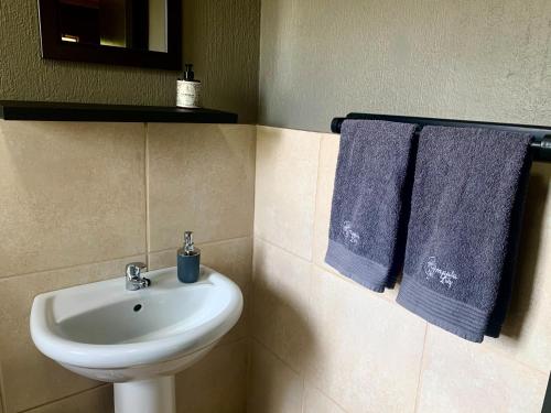 ein Badezimmer mit einem weißen Waschbecken und blauen Handtüchern in der Unterkunft Impala Lily in Marloth Park
