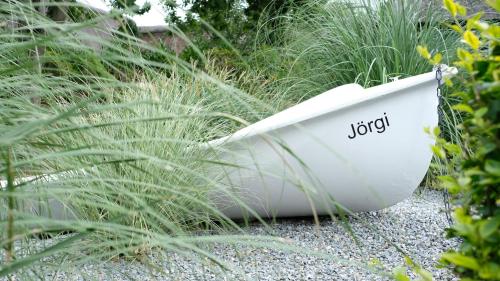a white boat sitting on the gravel near some tall grass at Hus op de Diek in Sankt Peter-Ording