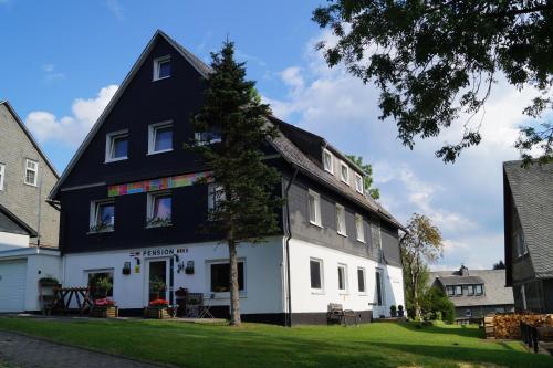 een zwart-wit huis met een boom voor bij Hotel Pension De Gasterei in Winterberg