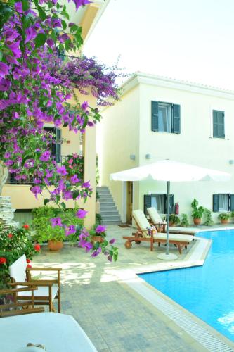 uma piscina com cadeiras e um guarda-sol ao lado de um edifício em Sparto Village em Meganisi