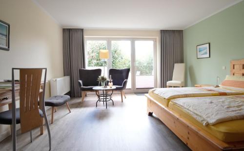 a bedroom with a bed and a table and chairs at Hus op de Diek in Sankt Peter-Ording