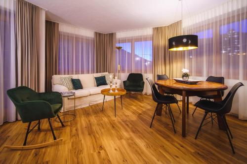 een woonkamer met een tafel en stoelen en een bank bij Das Landhaus Apartments Prägant in Bad Kleinkirchheim