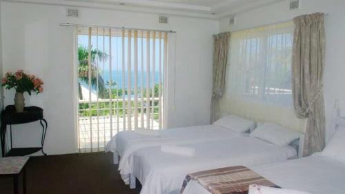 a bedroom with two beds and a large window at Thoko-Zani Beach House in KwaDukuza