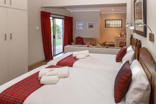 a bedroom with a large white bed with red accents at Argyll B&B in Oudtshoorn