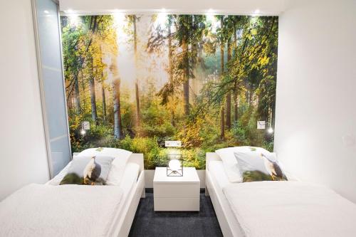 a room with two white couches and a forest mural at Altstadt-Chalet @Conny's in Brilon