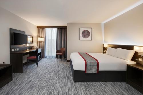 a hotel room with a large bed and a desk at Ramada by Wyndham Leeds East in Leeds