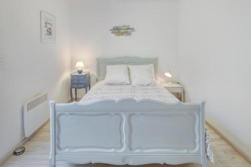 een wit bed in een witte kamer met een bedframe bij La Marinière in Pléneuf-Val-André