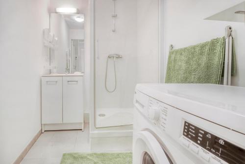 een witte badkamer met een douche en een wasmachine bij La Marinière in Pléneuf-Val-André