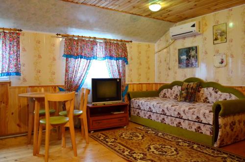 a bedroom with a bed and a tv and a table at Cottages On Gdantsevskaya Street in Kryvyi Rih