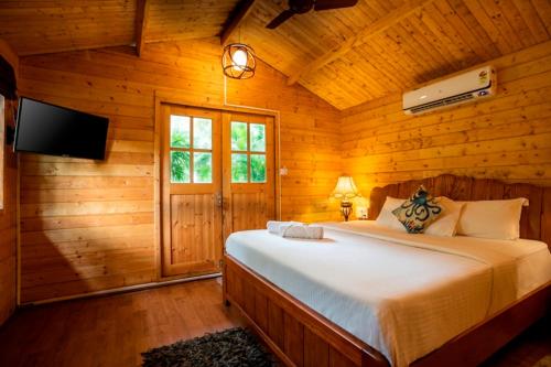 a bedroom with a bed in a wooden cabin at Montego Bay Beach Village - Morjim in Morjim