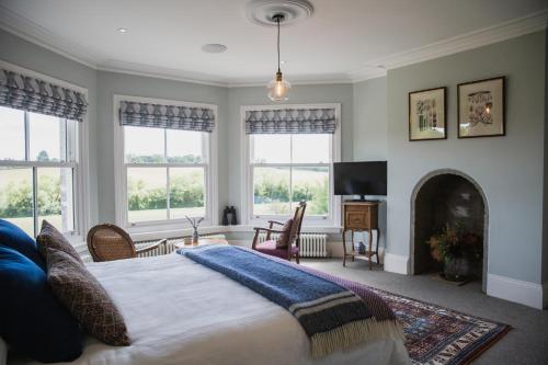 a bedroom with a bed with a fireplace and windows at Bridstow Guest House in Ross on Wye