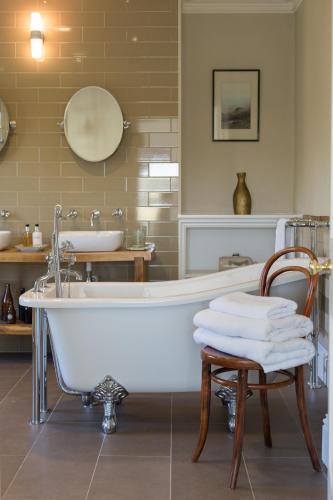 a bathroom with a tub and a chair and a sink at Bridstow Guest House in Ross on Wye