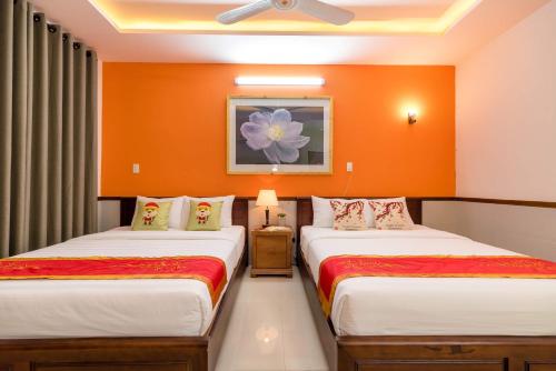 two beds in a room with orange walls at Luna Rossa Villa in Hoi An