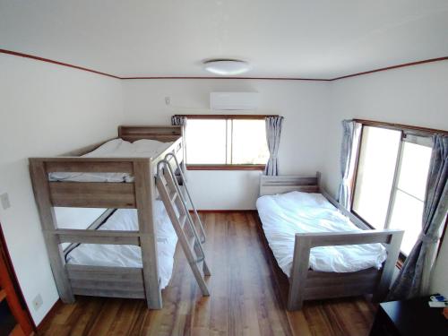 a room with two bunk beds and two windows at ツバメハウス in Tenri