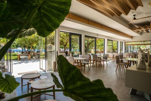 - un restaurant avec des tables, des chaises et de grandes fenêtres dans l'établissement Zoe Seaside Resort, à Gialova