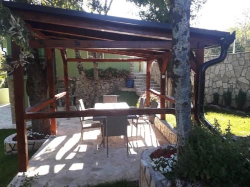 a patio with a table and chairs under a wooden pergola at Green House Source Vrilo in Tomislavgrad