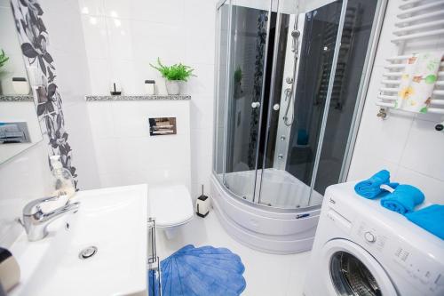 a bathroom with a shower and a washing machine at Family Homes - Apartamenty Abrahama in Władysławowo
