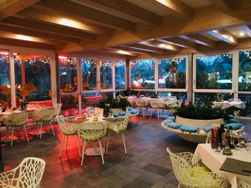ein Restaurant mit Tischen und Stühlen in einem Zimmer mit Fenstern in der Unterkunft Villa Franca in Nago-Torbole