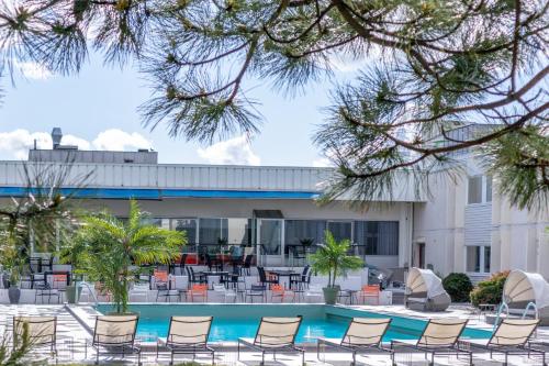 a pool with chairs and tables in front of a building at Apple Hotel & Konferens Göteborg in Gothenburg