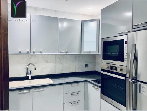 a white kitchen with a sink and a refrigerator at Ruve Jeddah Hotel in Jeddah