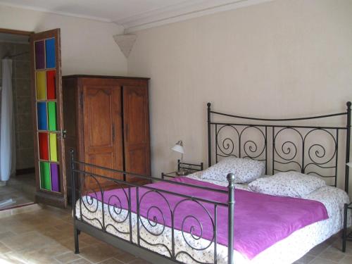 - une chambre avec un lit et une couverture violette dans l'établissement Le Petit Bois, à Château-la-Vallière
