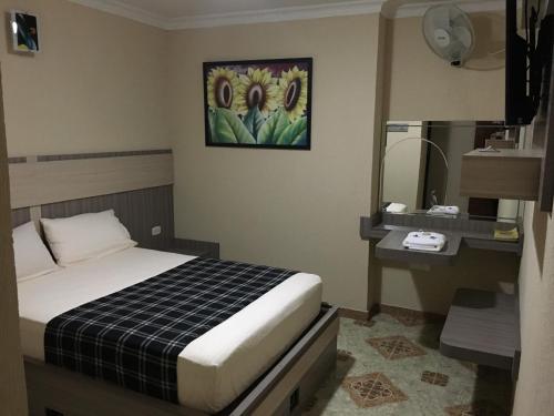 um pequeno quarto com uma cama e um espelho em Hotel Don Juan em Guadalajara de Buga