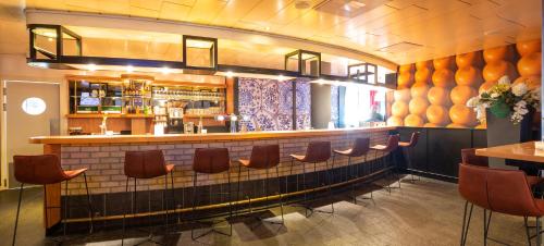 a bar with a row of chairs in a restaurant at Best Western Plus Amsterdam Airport Hotel in Hoofddorp